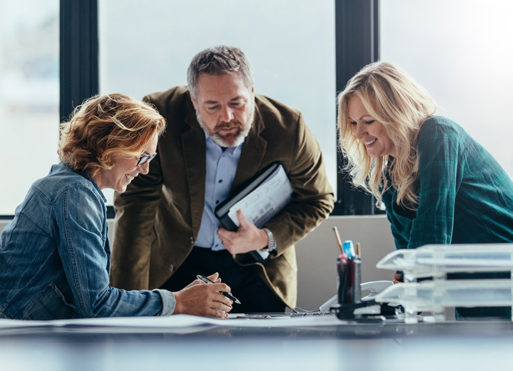 Three people smiling and discussing work